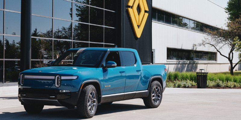 A Rivian truck in front of a Rivian building.